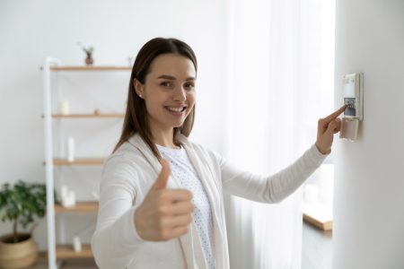 Smiling woman setting the alarm for apartment security