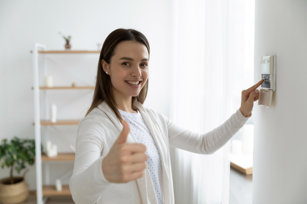 Smiling woman setting the alarm for apartment security