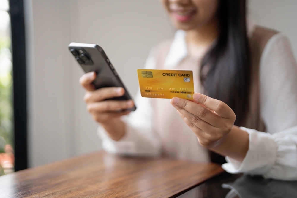 Woman paying bills on a smartphone with a credit card