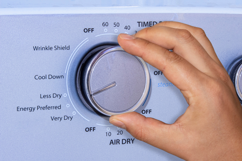 Person Turning Dial on a Dryer