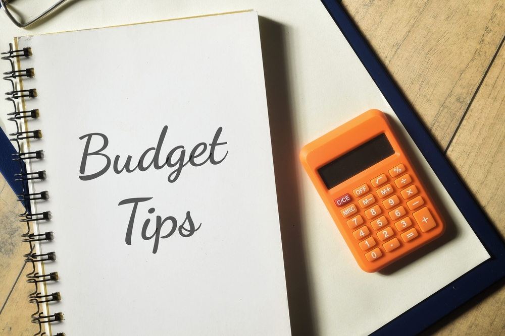 Budget tips concept on notebook with orange calculator