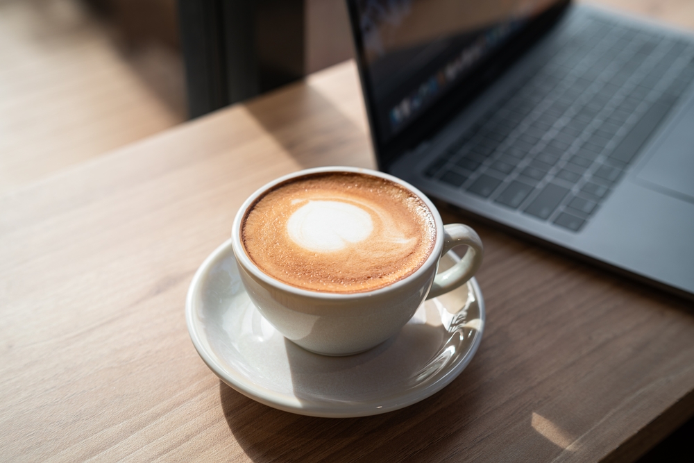 Close up of hot coffee and laptop at a cafe