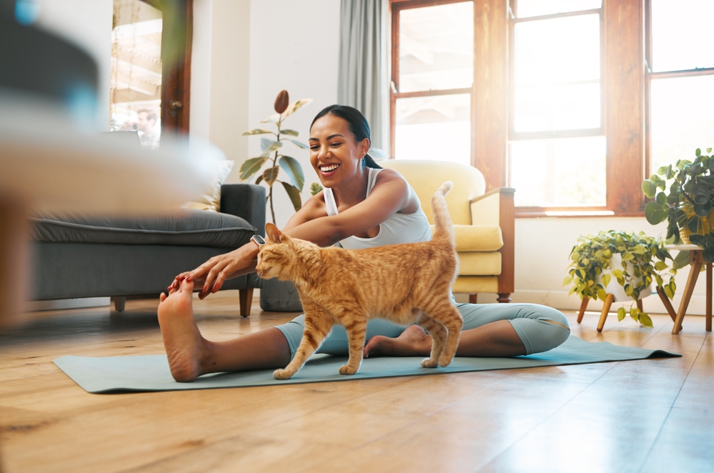 Woman doing yoga with cat in her pet-friendly apartment