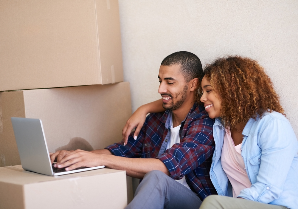 Couple renting an apartment on a laptop with boxes