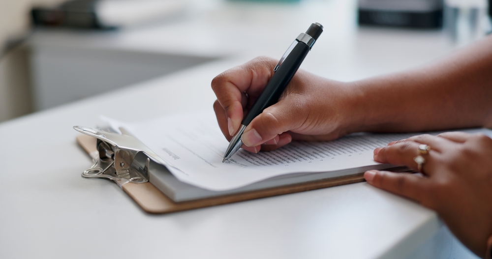 Close-up of hand signing documents for affordable housing programs